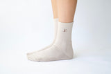 close-up of the embroidered luméa logo on the taupe pilates sock